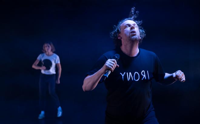 Bühnenszene von Oh Man! … 2 Schauspieler*innen in Bewegung auf dunkler Bühne