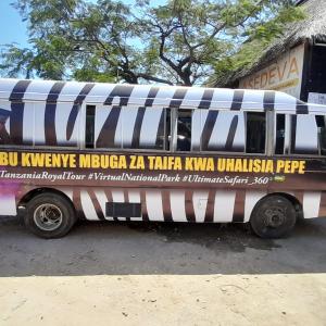 The Dadalada (Tanzanian bus) is home to the Ultimate Safari installation. It is covered with a zebra pattern and a performer with VR glasses